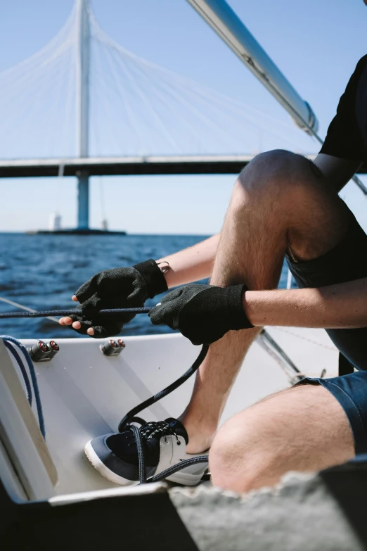 the man sits on a boat near the bridge