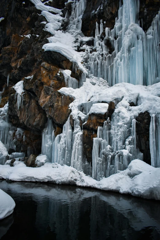 a man sitting on the rocks in front of some frozen waterfalls