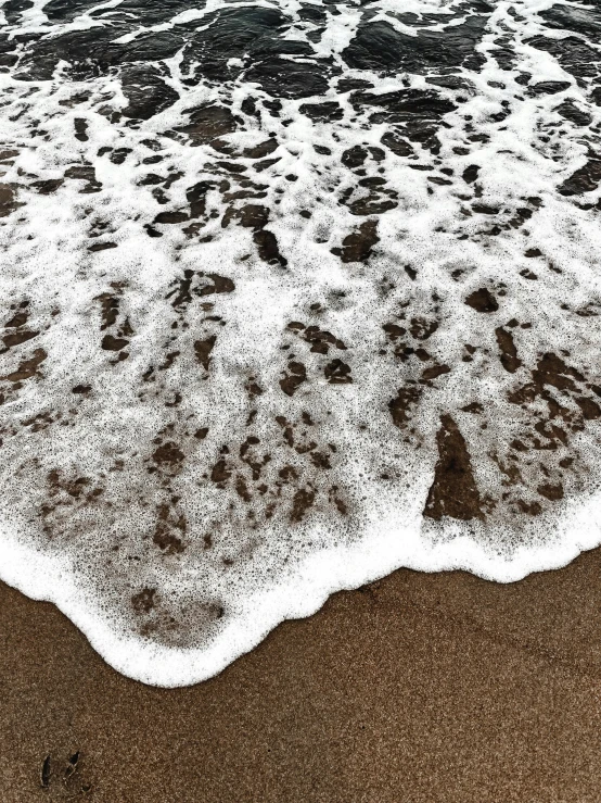 two people standing on the beach next to the ocean