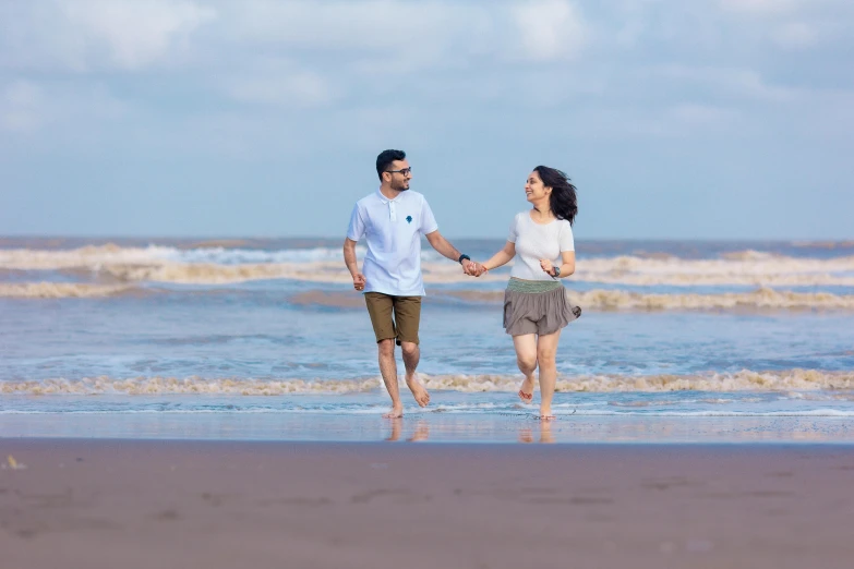 an asian couple is walking on the beach with a dog