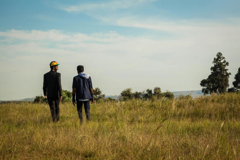 two men standing next to each other in a grass covered field