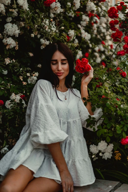 a young woman with dark hair is holding flowers