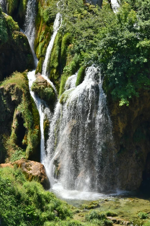 water falls with mossy vegetation and a white man on a rocky cliff