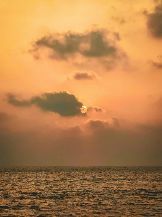 an orange sunset in the sky behind the water