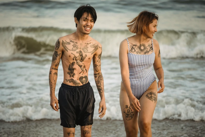 the young man and woman are walking on the beach