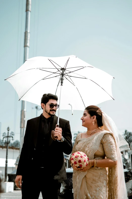 the bride and groom hold an umbrella under an umbrella