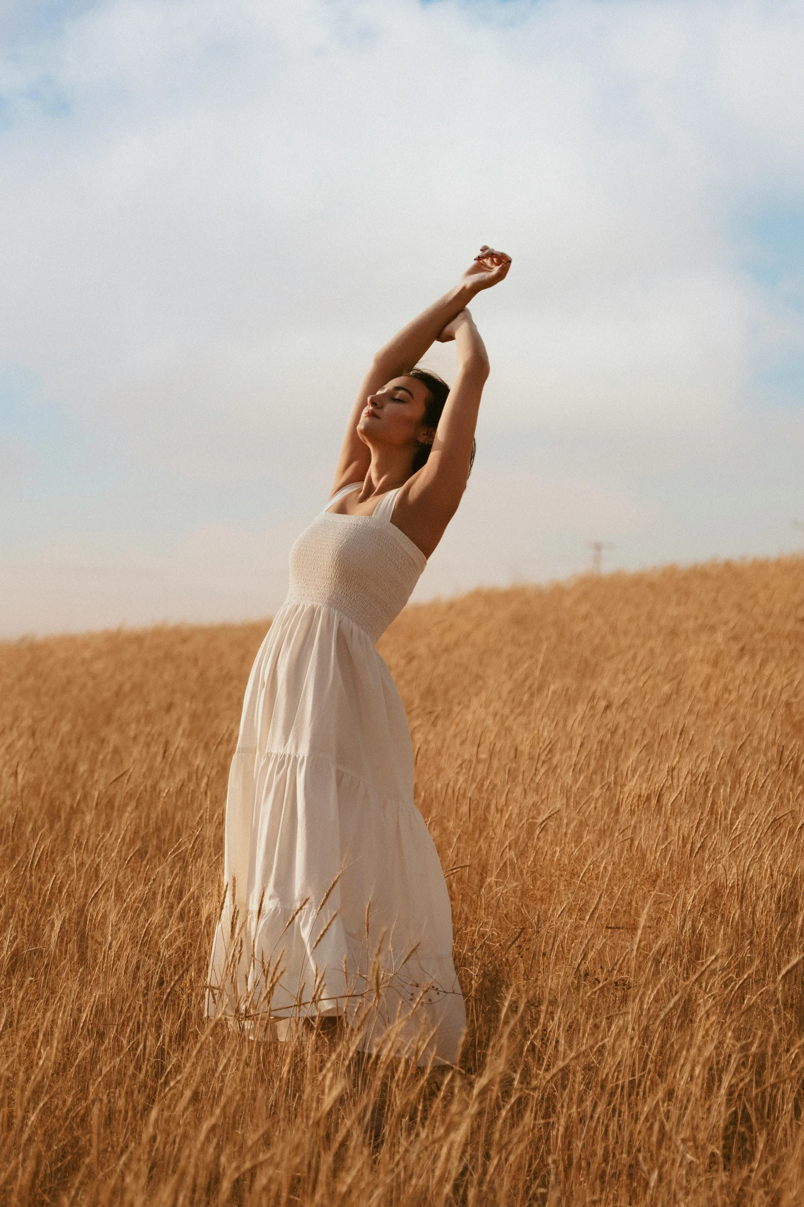 a woman in a white dress poses for a pograph in a field