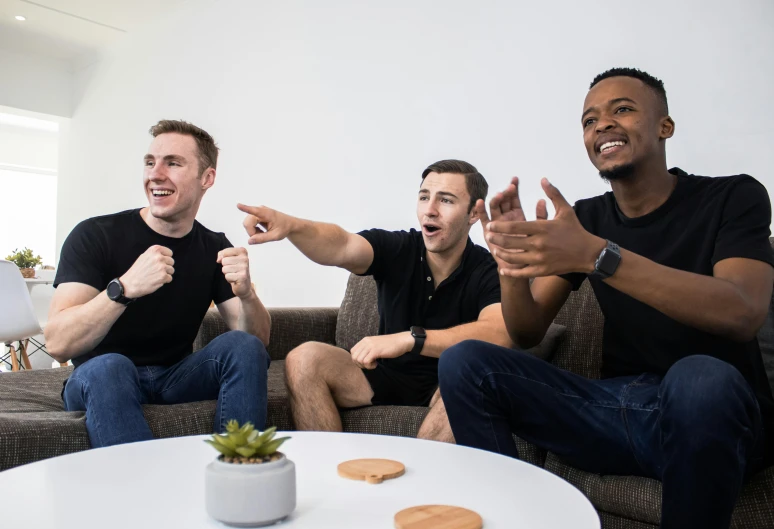 three men sitting on a couch with one pointing up