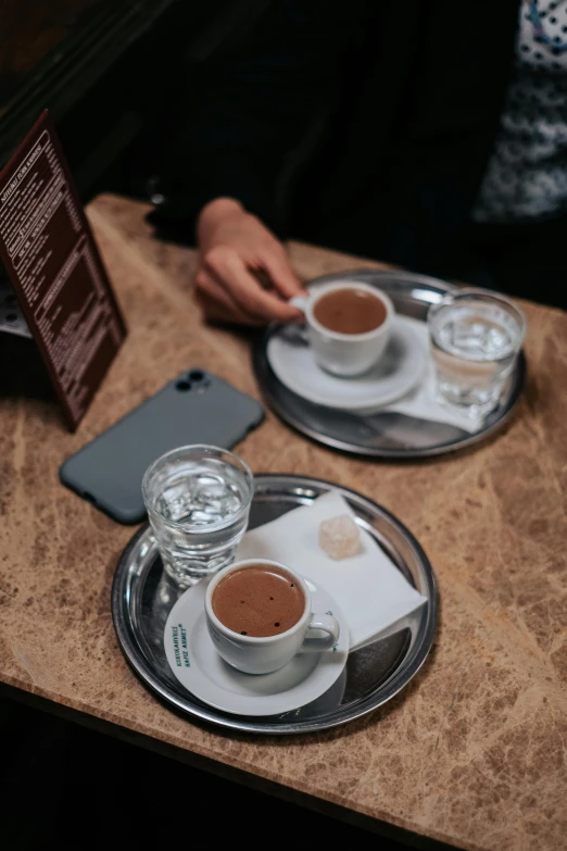 two small glasses of  chocolate are on a plate