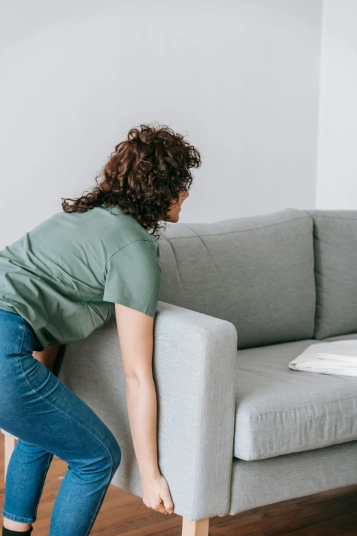 a woman holding up a sofa for her furniture to move