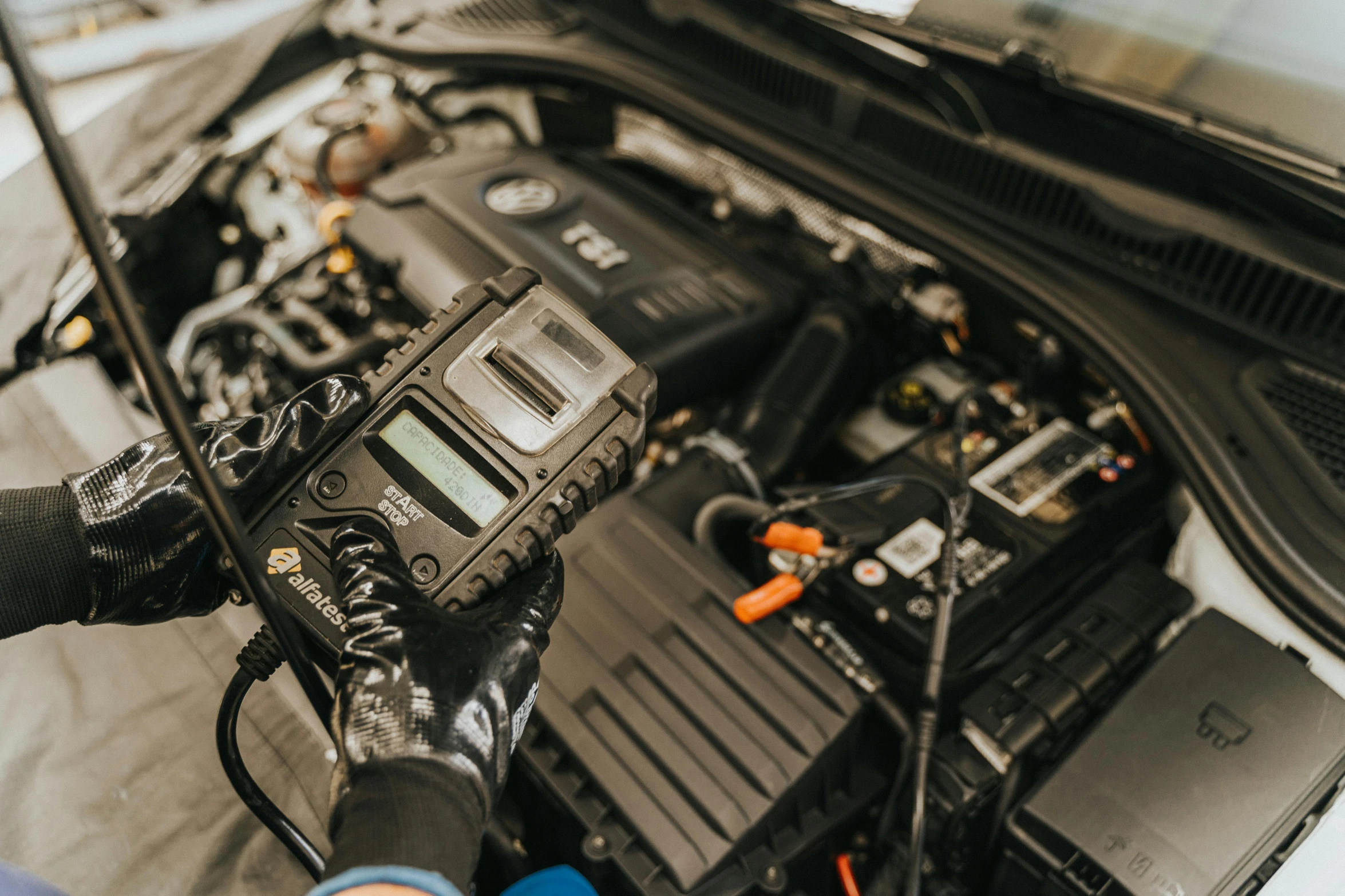 someone using a power meter to check the battery on a car