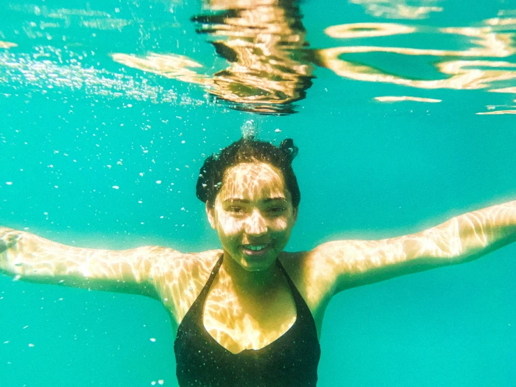 a woman floating under the water in a swimming suit