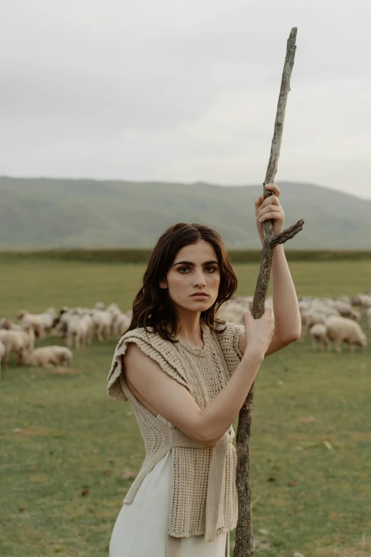 a girl is holding a stick in front of sheep