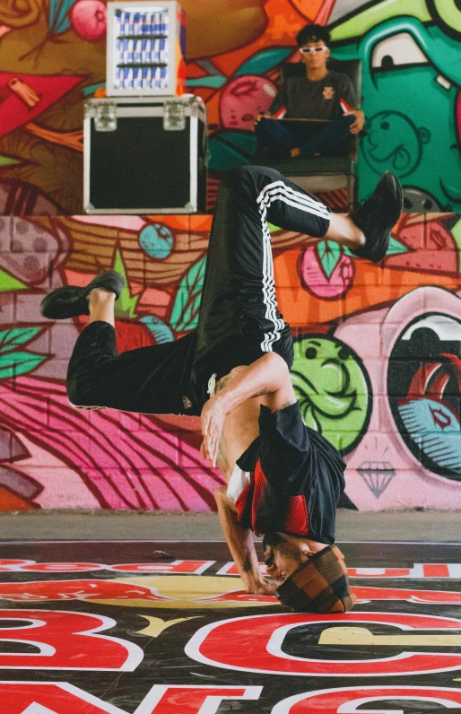 a woman doing a handstand in front of a graffiti wall