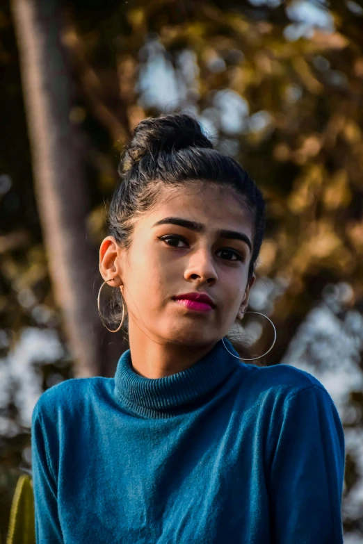 a woman with large earrings and a turtle neck shirt looking off into the distance