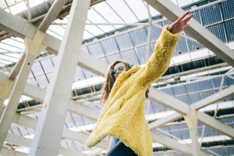 woman with black glasses is wearing a yellow sweater and a blue hat