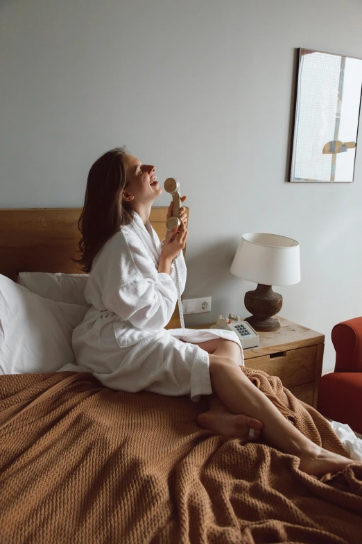 a woman sits on a bed while holding a doughnut