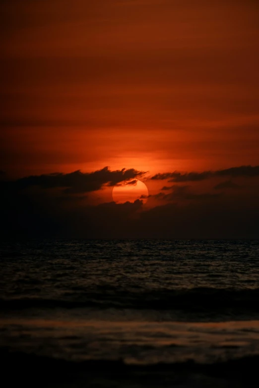 the sun setting on the horizon as seen from an ocean shore