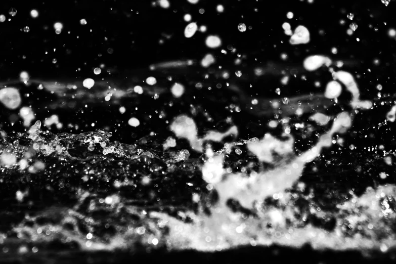 a black and white image of rain falling in to water