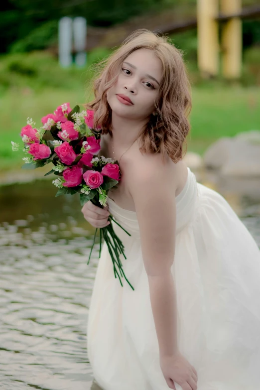 a woman in a dress posing in water holding flowers