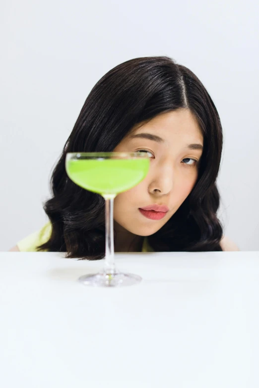 a young woman behind a table with a martini glass