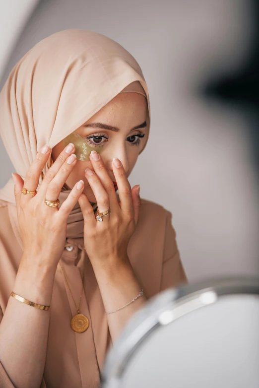 woman with gold rings holding up a golden substance in front of her face