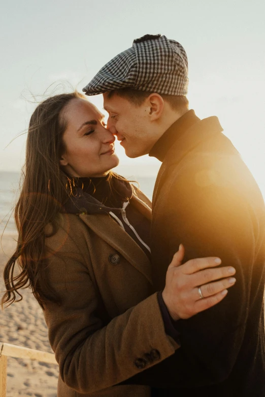 a young man and woman hugging by the ocean