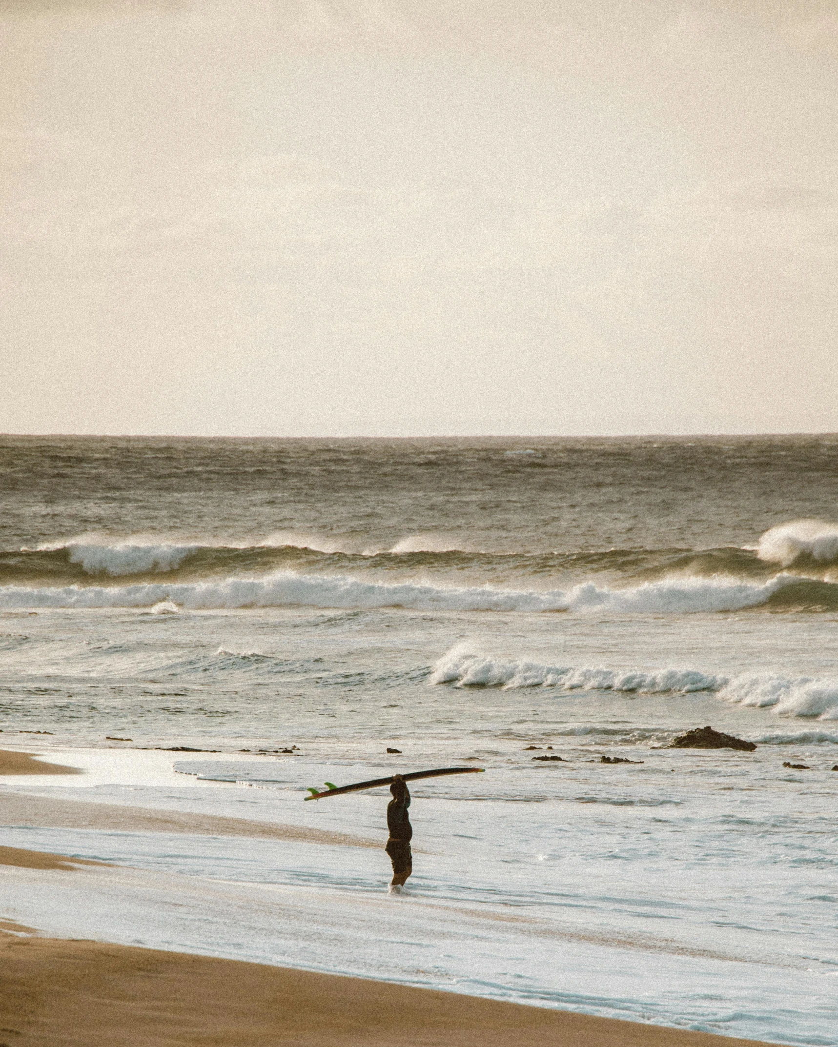 two people are walking along the ocean holding surfboards