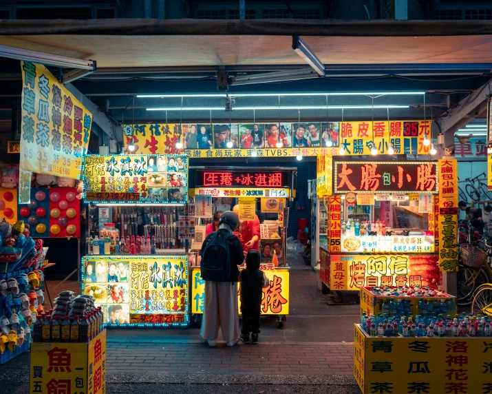 two people walking in front of store fronts at night