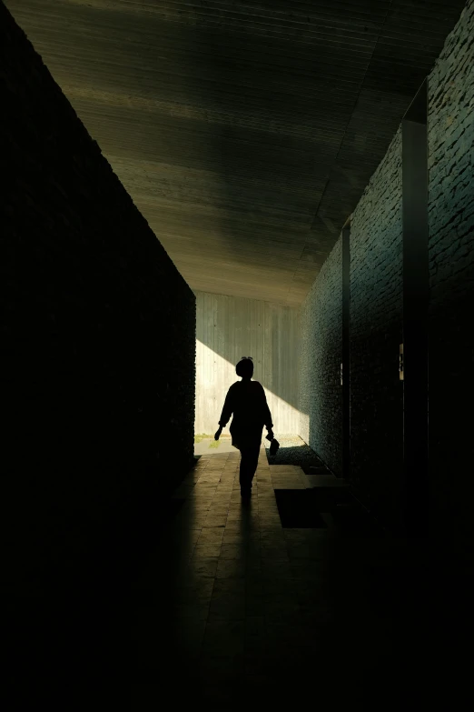 a person walking through a dark tunnel next to brick wall