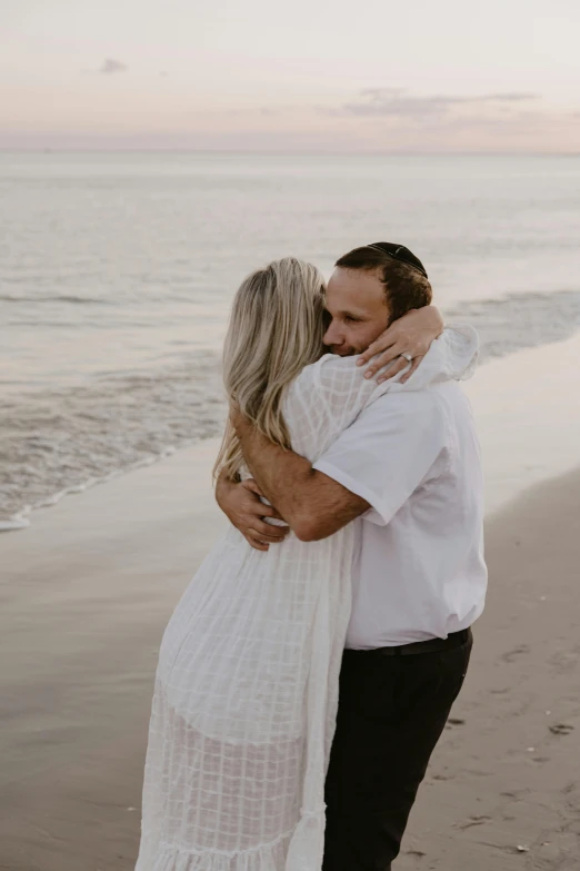 man and woman emcing each other while walking along the beach