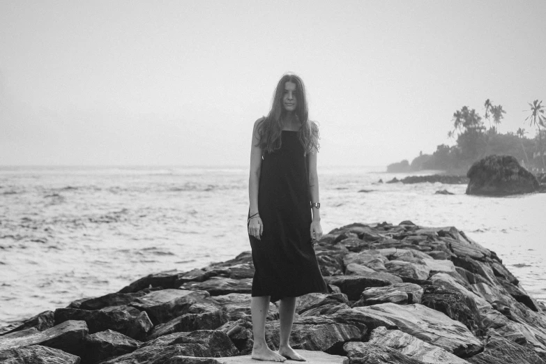 a young woman standing on top of a rock covered beach