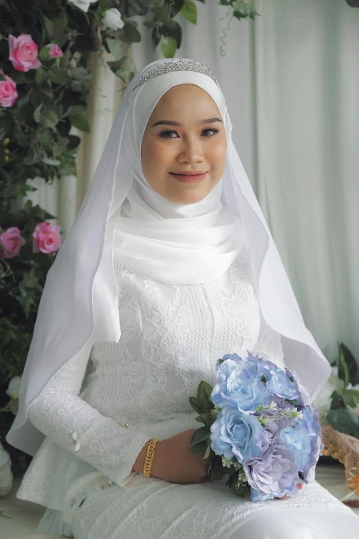 the girl dressed in wedding clothing sits with her bouquet
