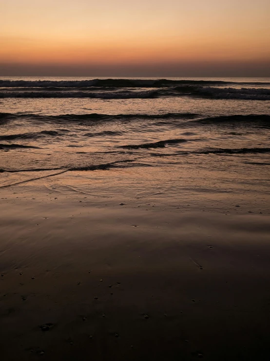 the ocean waves are going in at sunset