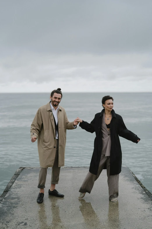 a man and woman posing on top of a pier