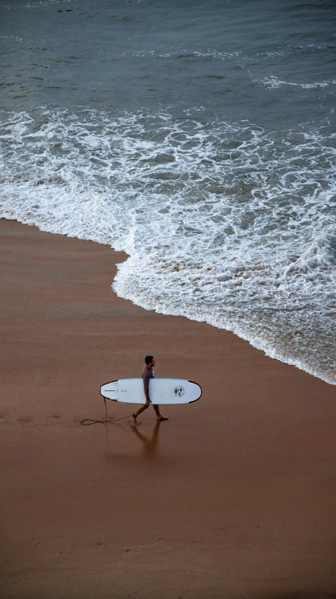 a man holding a white surfboard next to the ocean