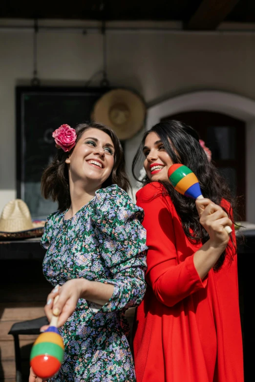 two woman in dresses are playing with colorful toys