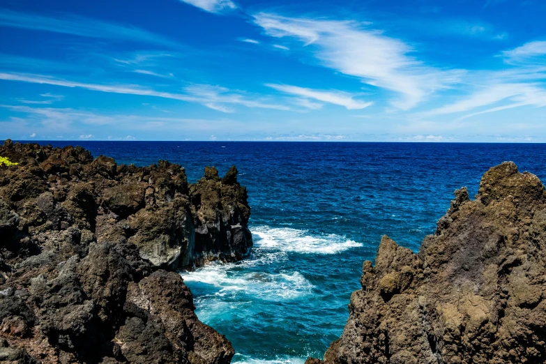 rocks at the edge of the ocean with a surfboard in their hand