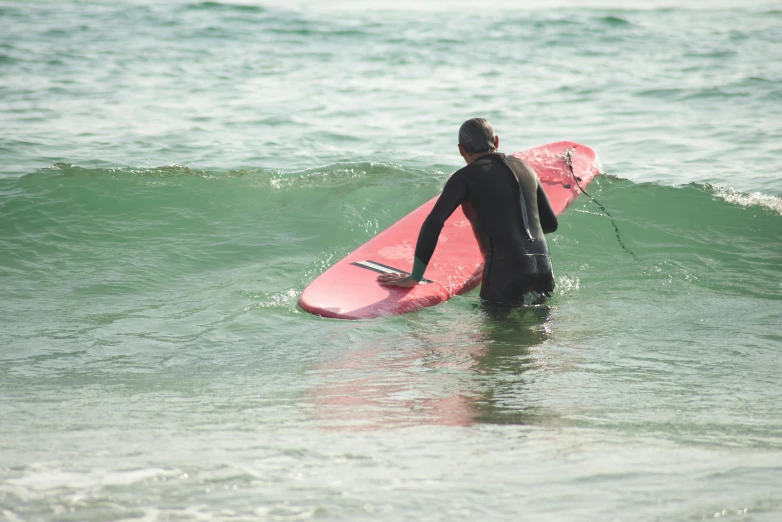 a man riding a pink surfboard in the ocean