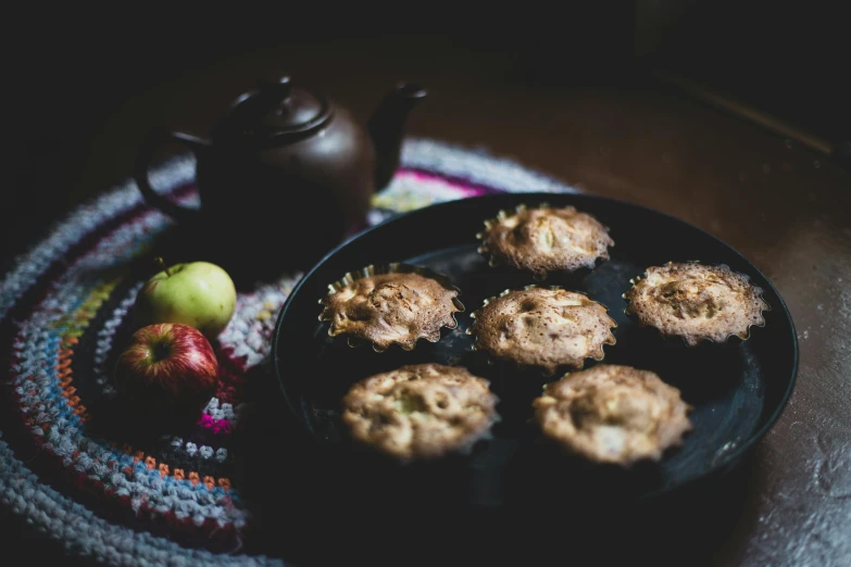 a plate with cookies and apples next to a tea pot