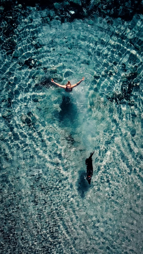 two swimmers in the water one is falling off his board