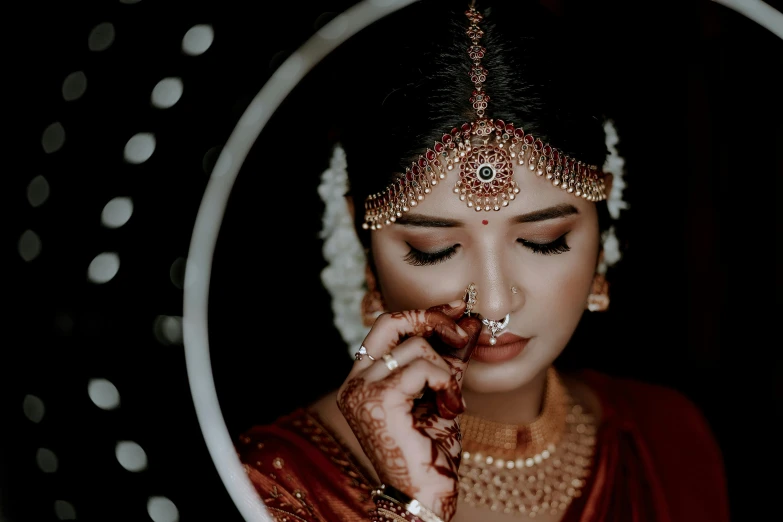 the woman is wearing gold jewelry and holding soing up to her face