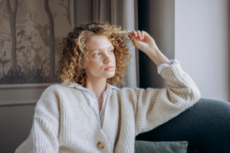 a woman wearing a cardigan and holding her hair up