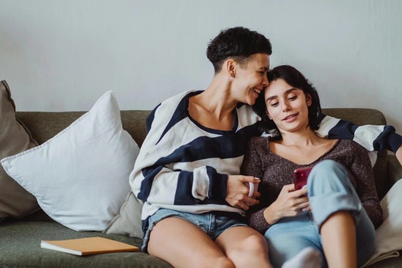 two friends looking at the cellphone on the couch