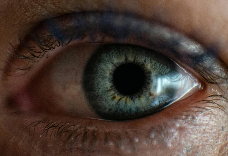 the center of a blue eye is showing light