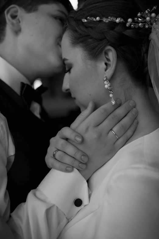 a bride kisses the groom and holds his hands around his neck