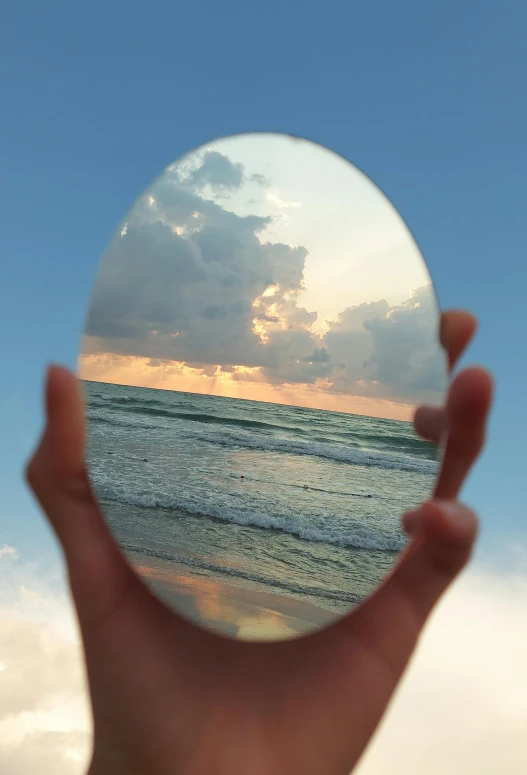 a hand holding up a small circular mirror