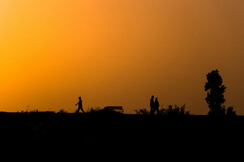 a sunset shows two people walking together in silhouette