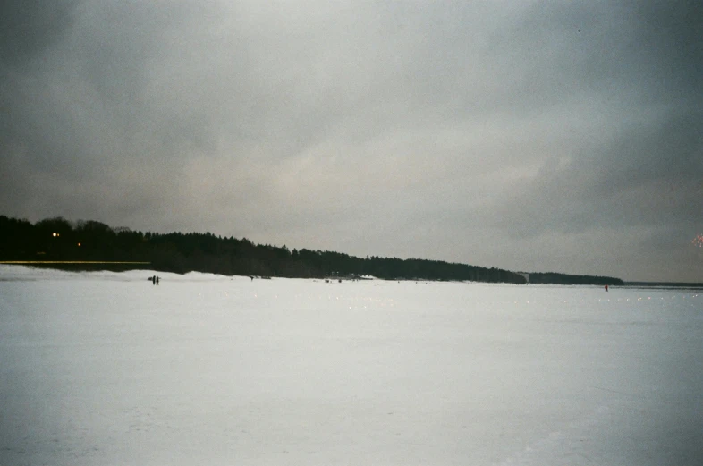 two skiers are in the snow next to a dark hill