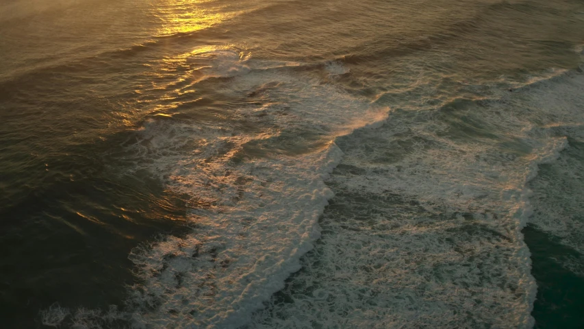 a beach with waves and the sun shining on the water